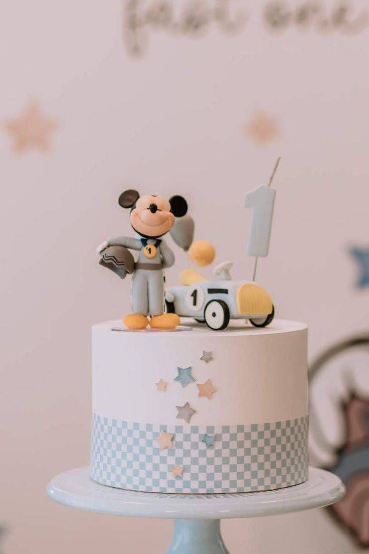 a mickey mouse birthday cake on a blue pedestal with stars and a checkered design