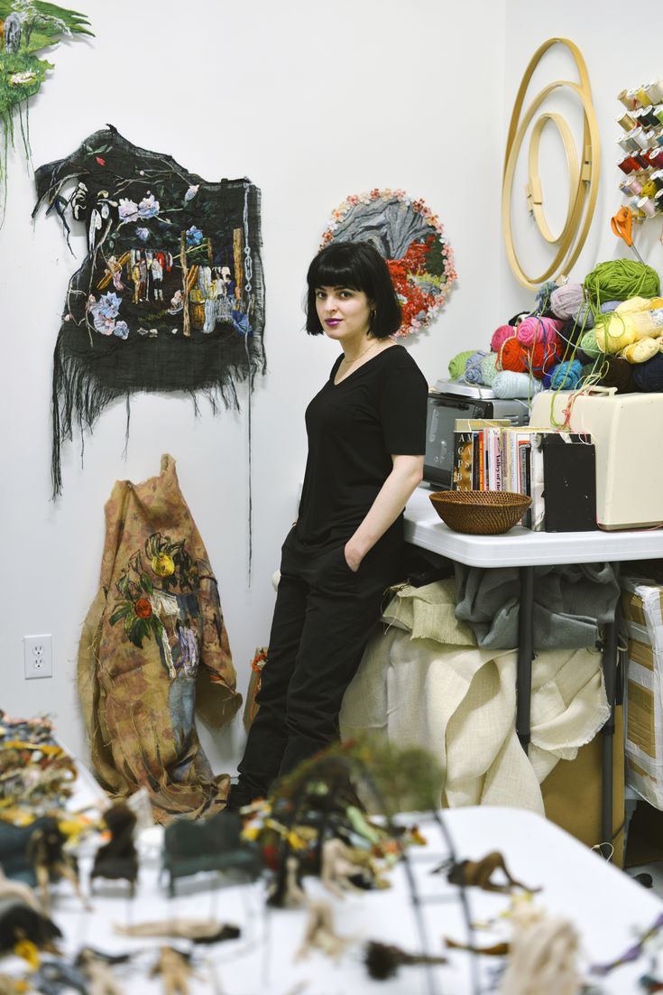 a woman standing in front of a table full of art and craft supplies on display