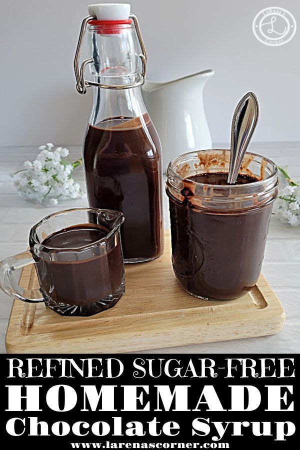 homemade chocolate syrup in glass jars with spoons on cutting board next to pitcher and jug