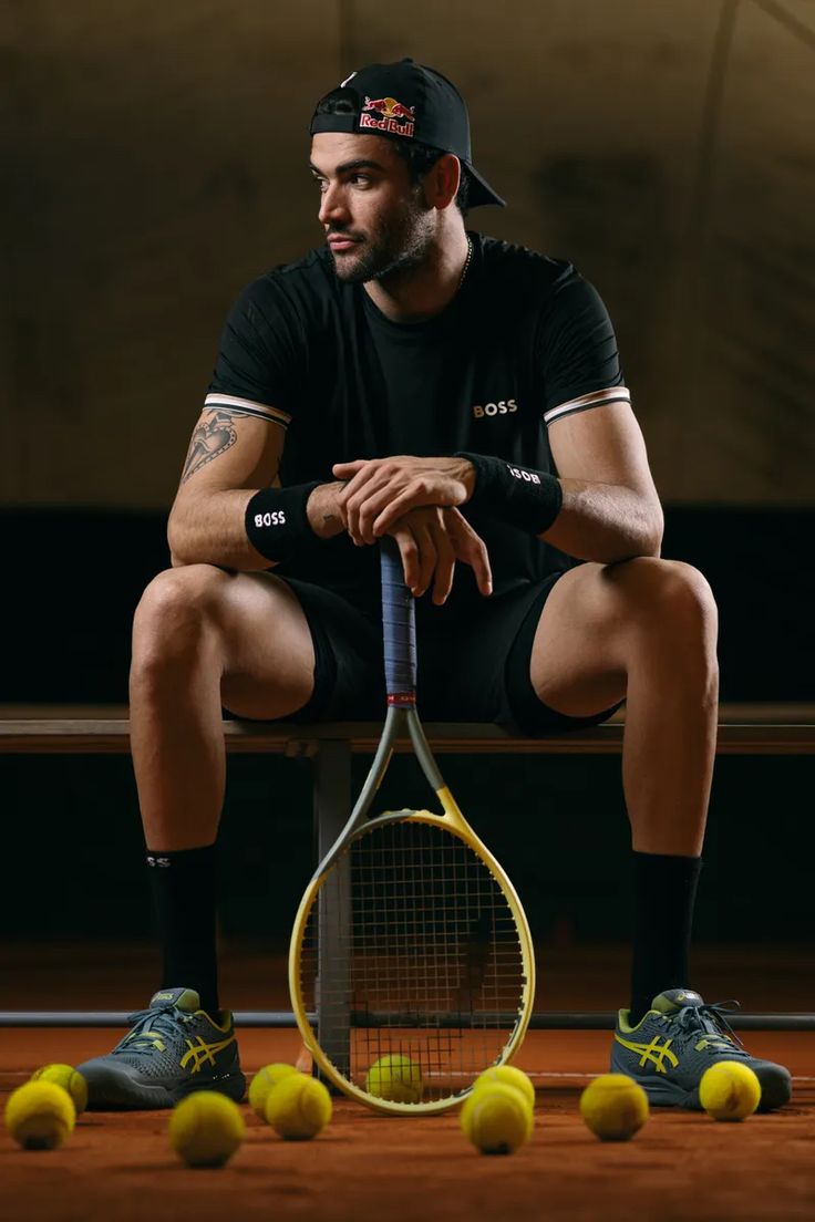 a man sitting on a bench holding a tennis racquet and four tennis balls