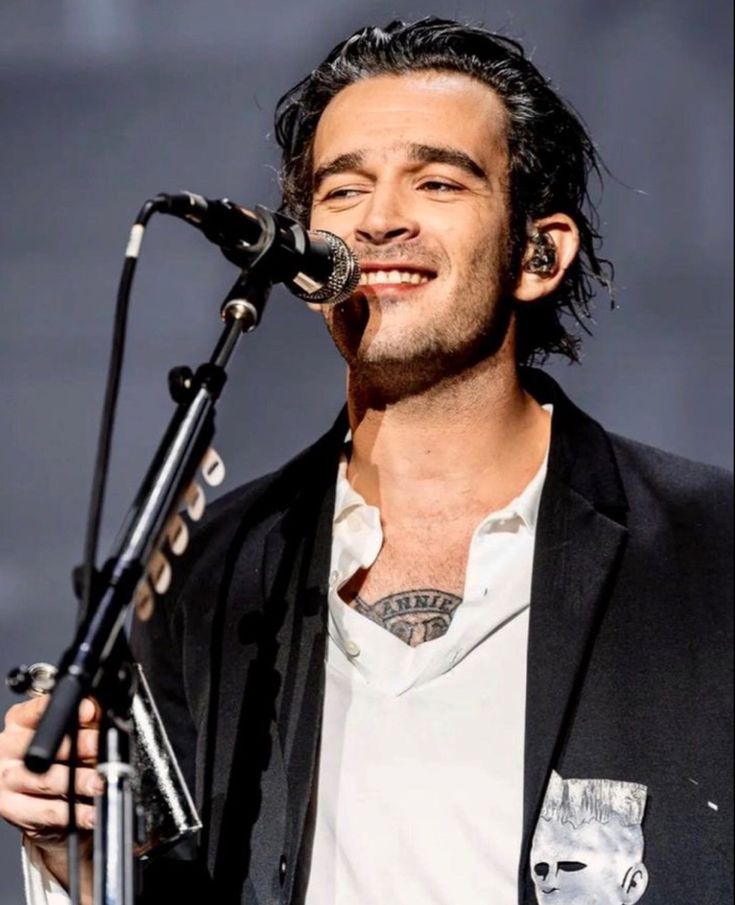 a man that is standing in front of a microphone and singing into a microphone stand