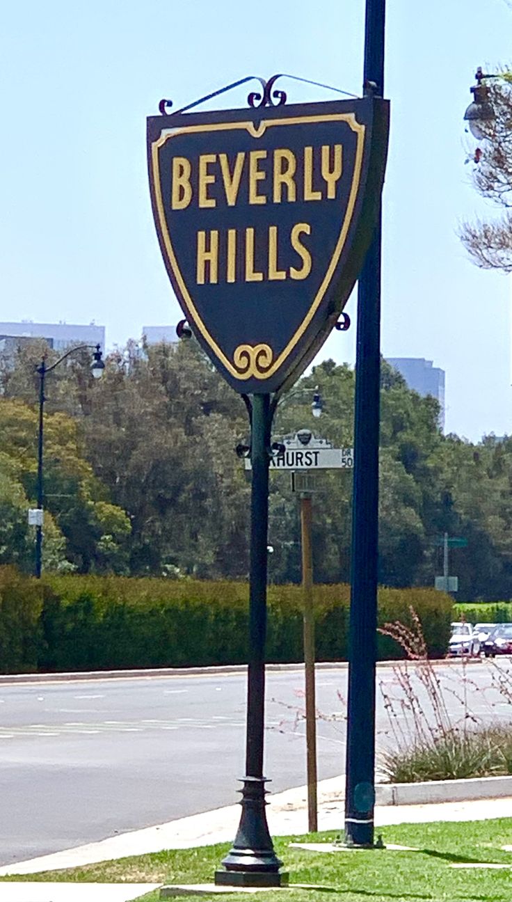 a sign that says beverly hills on it's side in front of a street