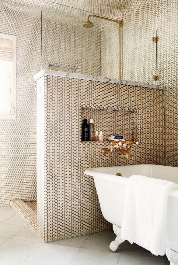 a white bath tub sitting in a bathroom next to a sink and shower faucet