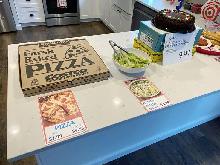 a pizza box sitting on top of a kitchen counter next to a bowl of salad