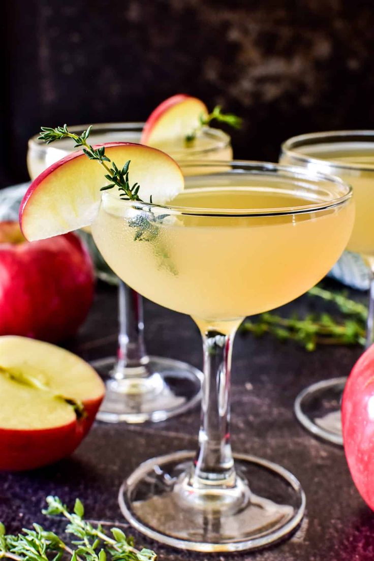 three glasses filled with apple cider and garnished with rosemary