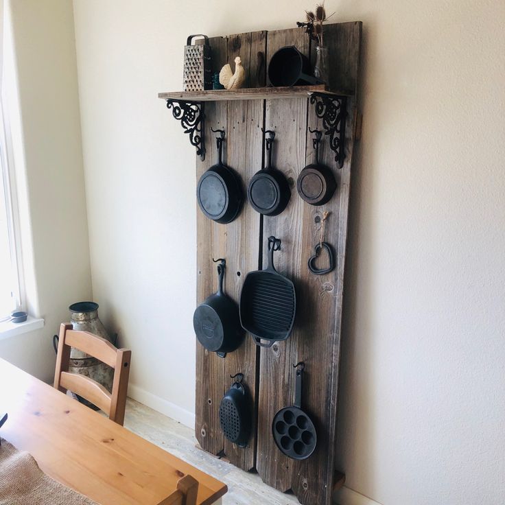 a wooden rack with pots and pans hanging from it's sides next to a dining room table