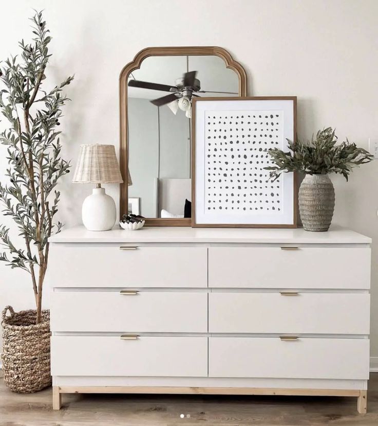 there is a white dresser with plants and pictures on the top, and a mirror above it that says ikea malm dresser hack