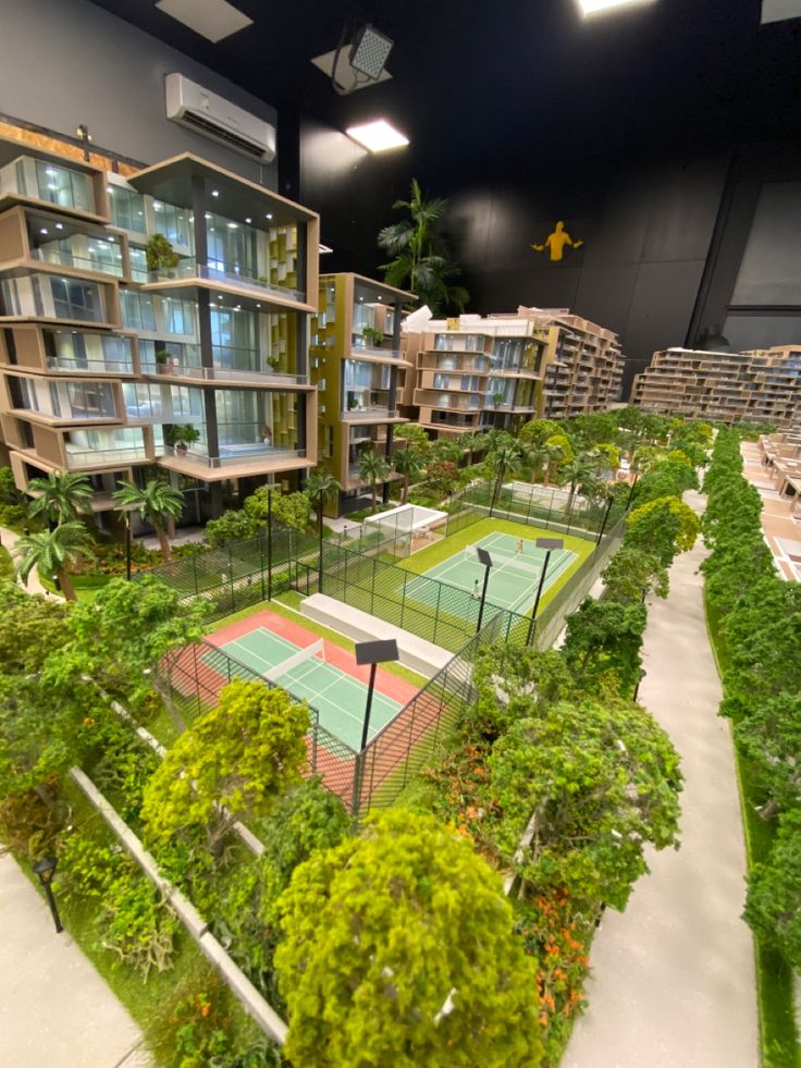 a model of a tennis court surrounded by trees and bushes in a building that looks like it is built into the ground