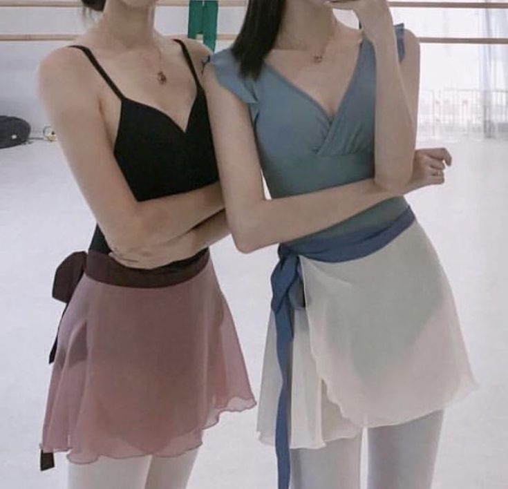 two young women standing next to each other in front of a white wall and floor