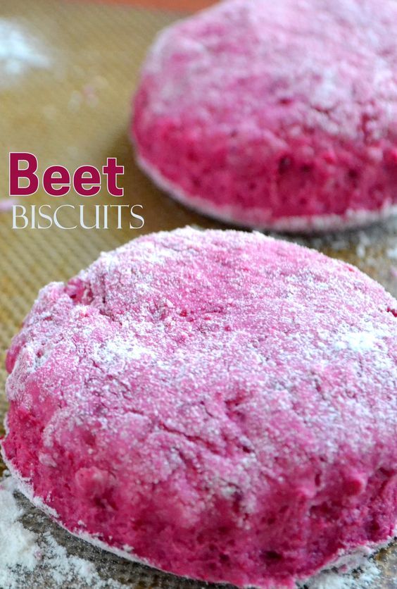 two round pastries covered in powdered sugar on top of a baking sheet with words beet biscuits