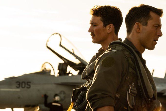 two men standing next to each other in front of an airplane