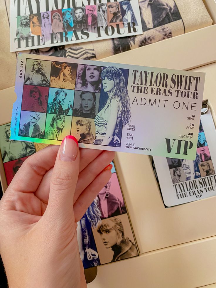 a person holding up a ticket for taylor swift the erase tour in front of some posters