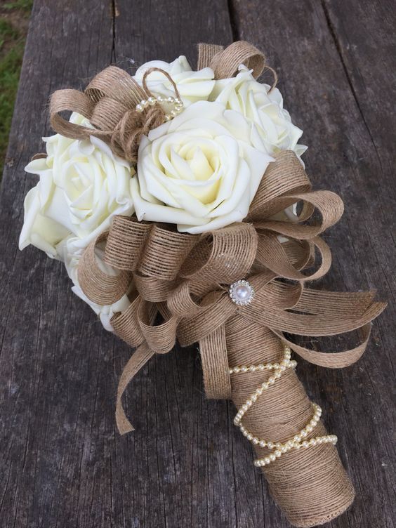 a bridal bouquet with white roses and pearls on it sitting on a wooden table