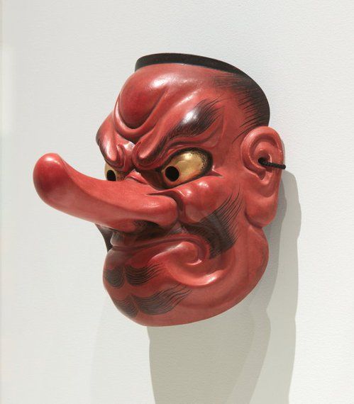 a red mask hanging on the wall with its tongue sticking out and eyes wide open