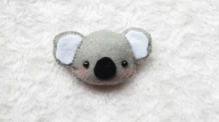 a small stuffed koala bear is laying on a white furnishing area with its eyes open