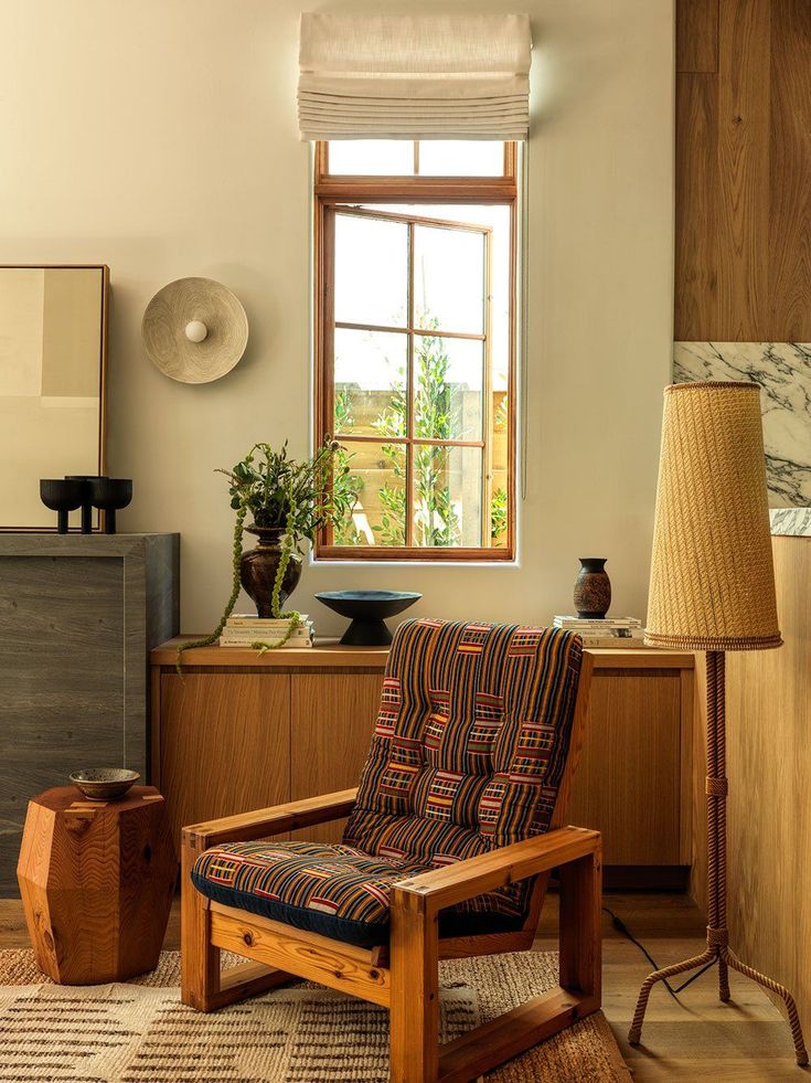 a chair sitting in front of a window next to a lamp