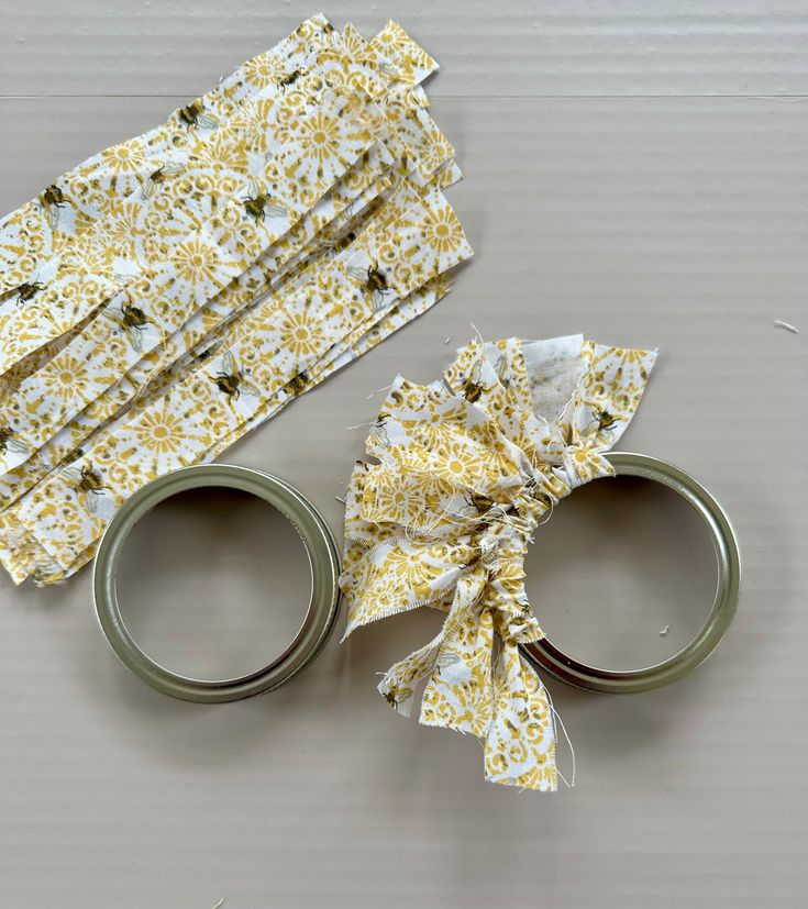 two pairs of scissors are sitting next to each other on a table with yellow and white fabric