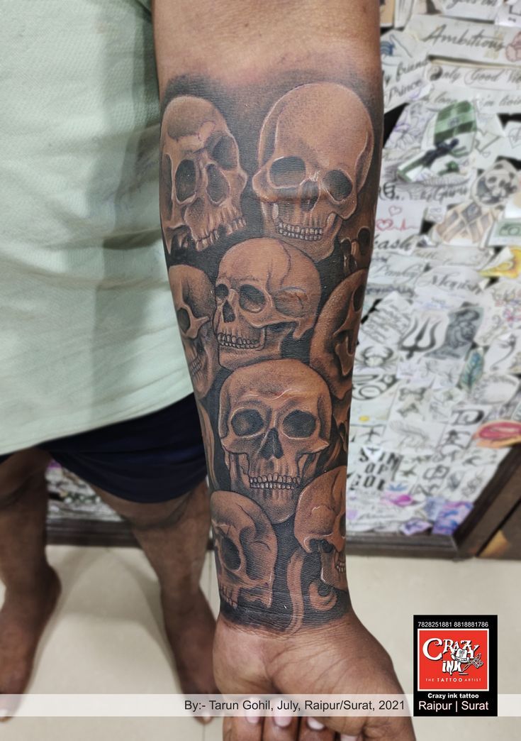 a man's arm with skulls on it and one hand holding the other up