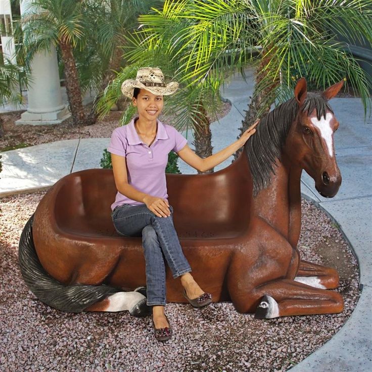 a woman sitting on top of a horse statue next to a palm tree and other animals