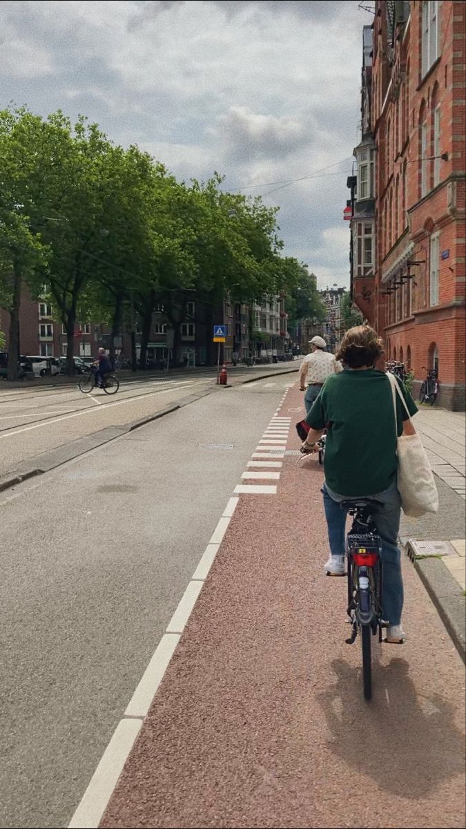 a person riding a bike down the side of a road next to tall brick buildings