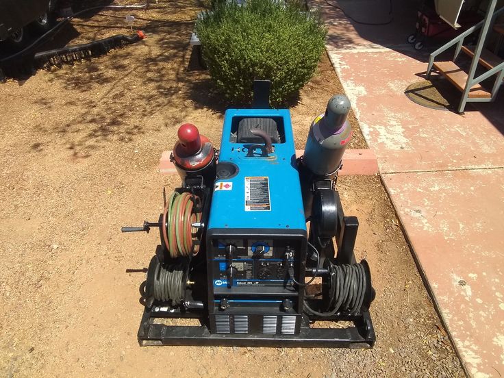 a small blue machine sitting on top of a dirt field next to a fire hydrant