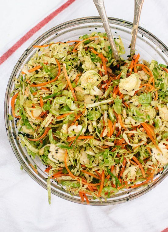 a salad with carrots, cauliflower and lettuce in a glass bowl