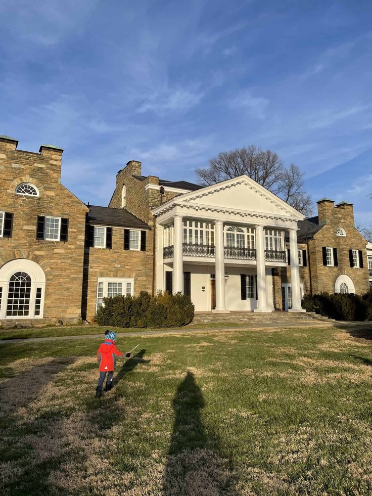 a young boy standing in front of a large brick building with columns and balconies