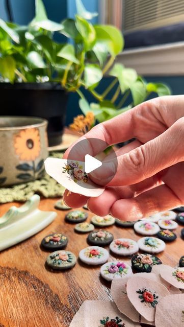 a person is holding up some buttons on a table with other things in the background