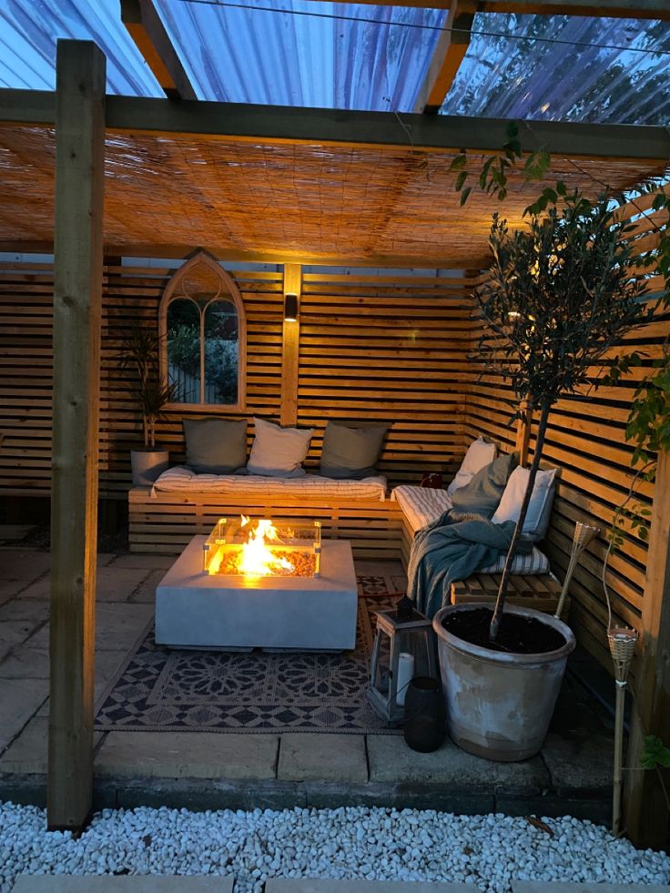 a fire pit in the middle of a patio with two couches and a potted plant