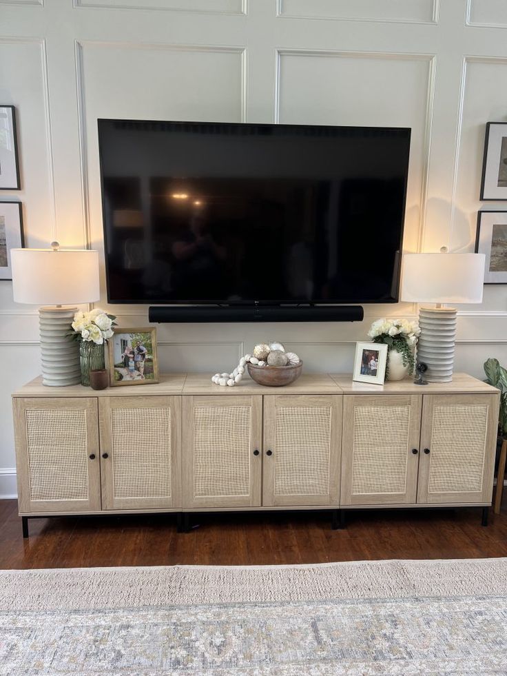 a flat screen tv mounted on top of a wooden entertainment center in a living room