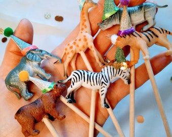 small toy animals on toothpicks in the palm of someone's hand