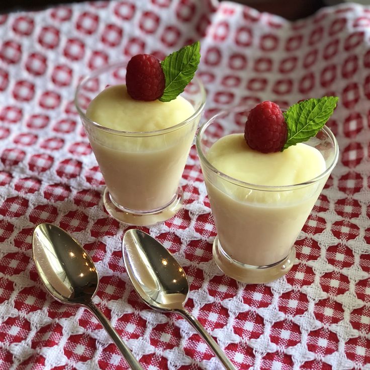 two desserts with raspberries sit on a red and white checkered tablecloth