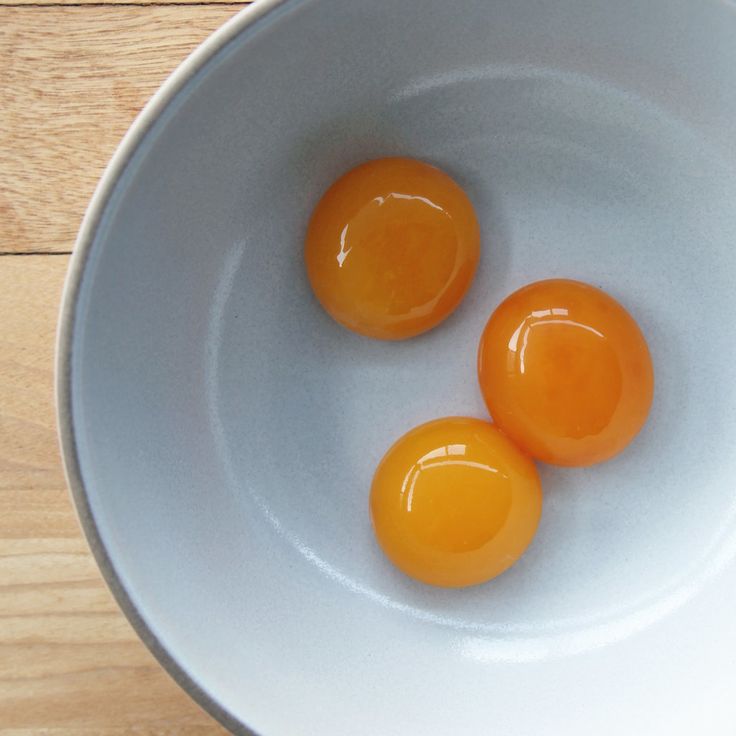 two eggs in a white bowl on a wooden table