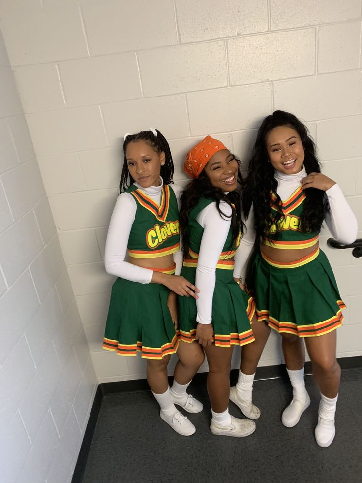 three girls in green and yellow cheerleader outfits posing for the camera with their arms around each other