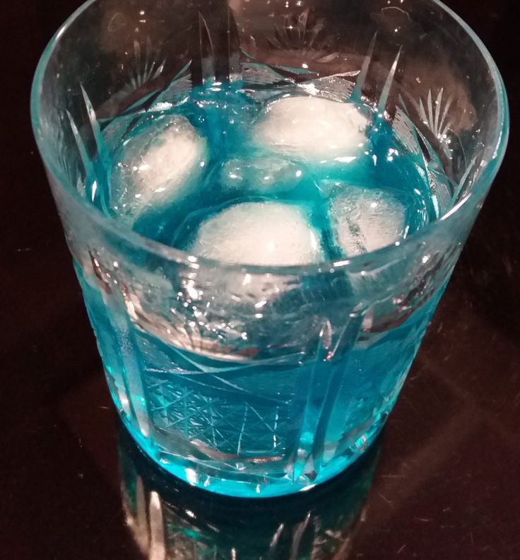 a glass filled with ice cubes sitting on top of a table