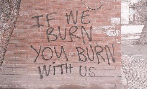 graffiti on the side of a brick building reads, if we burn you burn with us