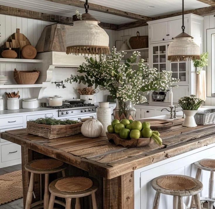 a kitchen with white cabinets and lots of counter space, including a wooden table topped with fruit