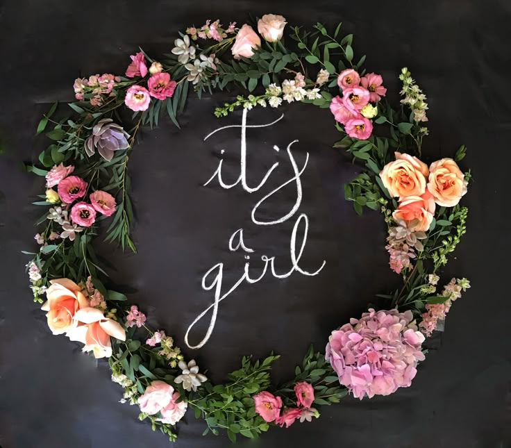 it's a girl written on a chalkboard surrounded by flowers