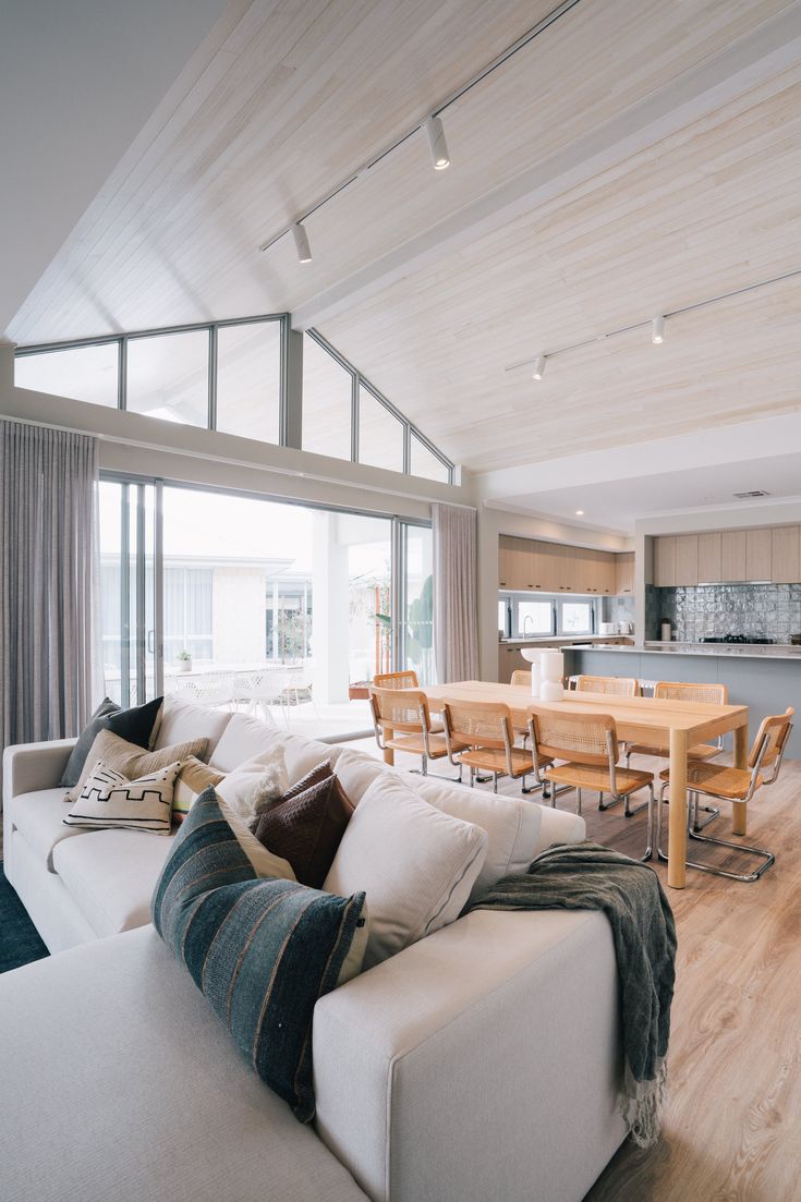 a living room filled with furniture next to a kitchen and dining room table on top of a hard wood floor