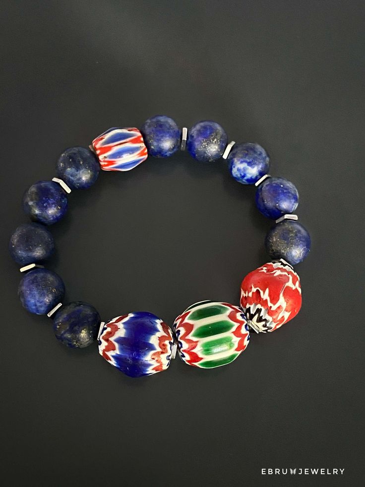 "The Lapis Lazuli Nepal Bracelet is irreplacable for the ones who like the energy of colors. The vibrant colors of handmade Nepal beads meet the beautiful lapis lazuli stones and their energy in this bracelet. Lapis Lazuli is a vibrant blue stone that's commonly worn for protection. This stone resonates with the throat and third eye chakras, bringing the wearer greater self knowledge, and encourages honesty and compassion. Therefore it helps with finding inner peace and encouraging confidence an Blue Gemstone Beads Bangle Bracelet, Blue Bangle Bracelets With Gemstone Beads, Blue Bangle Jewelry With Large Beads, Traditional Blue Bracelet For Gift, Blue Lapis Lazuli Bracelets With Natural Stones, Blue Gemstone Beads Bangle, Blue Gemstone Bead Bangle, Blue Gemstone Beads Bangle Jewelry, Sapphire Gemstone Beads Bracelet In Lapis Lazuli