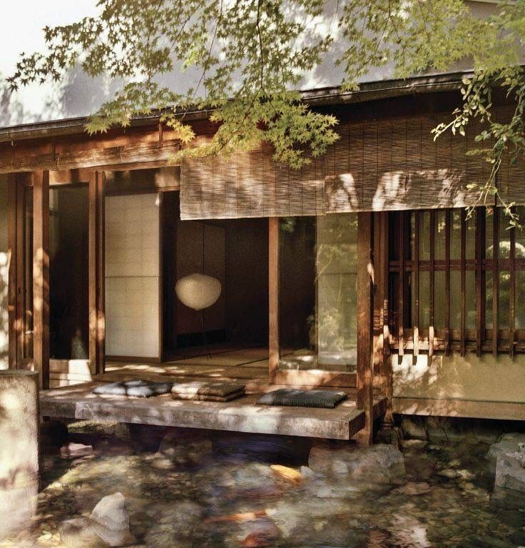 a japanese style house is shown in the woods with rocks on the ground and trees around it