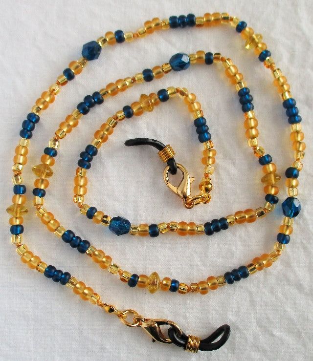 Always keep your reading glasses nearby using this blue & yellow beaded eyeglass chain! 26" in length, made with glass beads, beading cord, metal lobster clasps, and adjustable rubber holders. Lobster clasps make it easy to change the rubber holders, and an extra pair of holders included with every purchase. This blue & yellow beaded eyeglass chain will arrive in a gift box, ready to give as a present or to keep and store. Back to Beaded Eyeglass Chains Adjustable Czech Glass Beaded Necklaces With Lobster Clasp, Adjustable Gold Beaded Necklaces Nickel Free, Adjustable Gold Beaded Necklace Nickel Free, Adjustable Gold Nickel-free Beaded Necklace, Adjustable Metal Beaded Necklace With Lobster Clasp, Adjustable Blue Beaded Necklace With Lobster Clasp, Beaded Eyeglass Chain, Beading Cord, Chain Lanyard