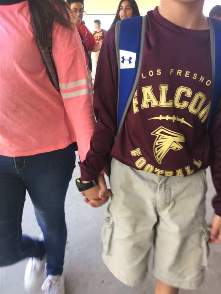 two people holding hands and walking through an airport terminal with other people in the background