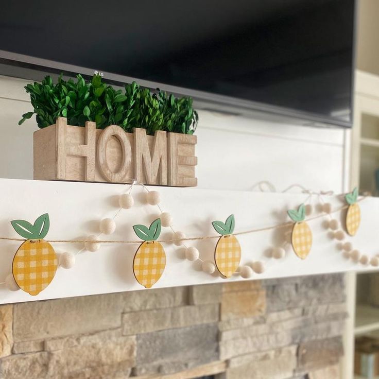 some pineapples are hanging on a mantle with the word home spelled out above them