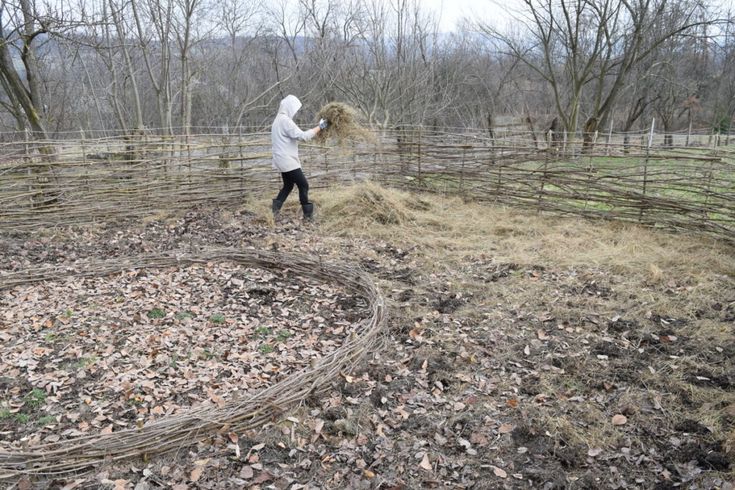 a woman in white jacket standing on top of a pile of leaves