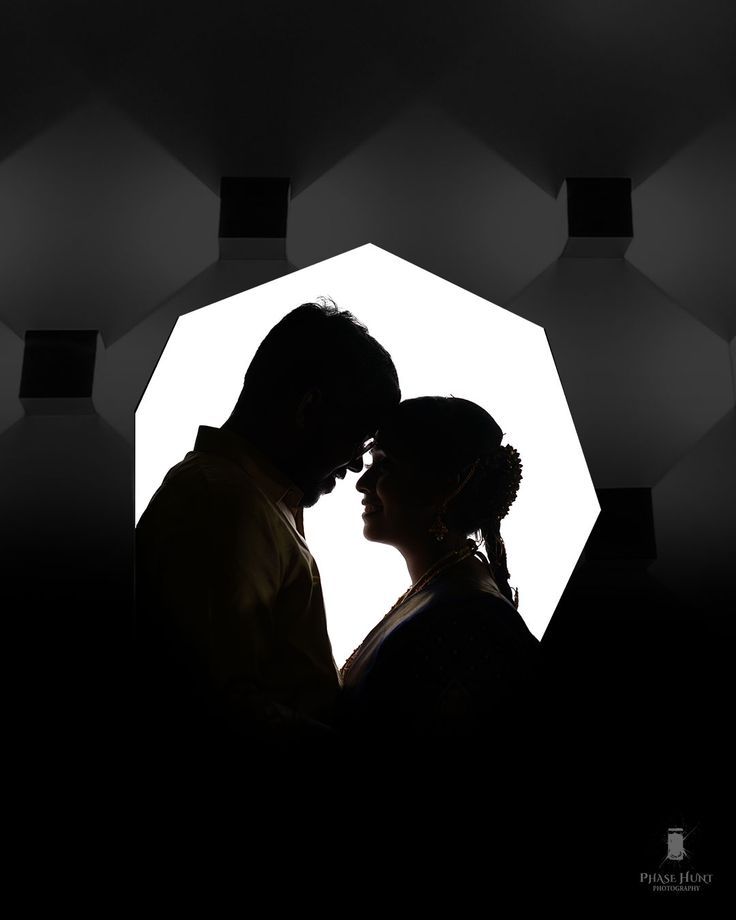 a man and woman standing next to each other in front of a white wall with hexagons