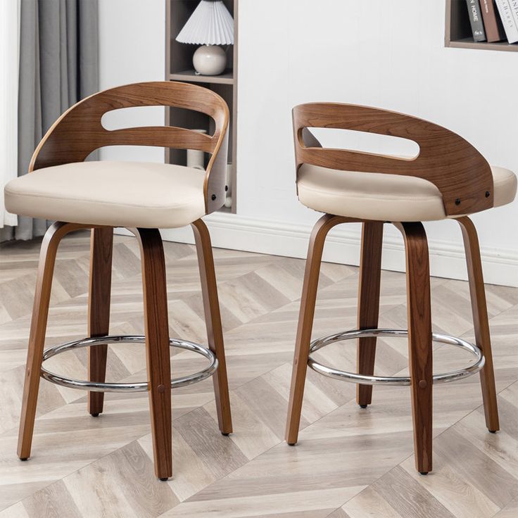 two wooden barstools sit in front of a bookcase