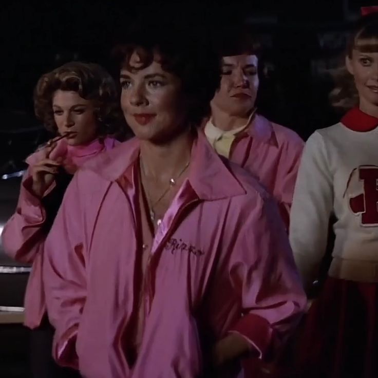 three women in pink jackets standing next to each other with one woman looking at the camera