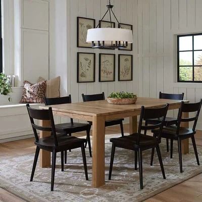 a dining room table with black chairs and a rug on the floor in front of it