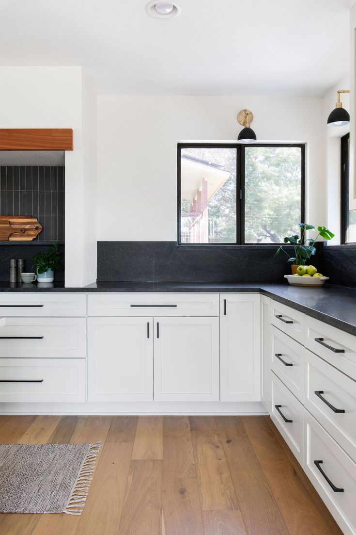 a kitchen with white cabinets and black counter tops is seen in this image from the front